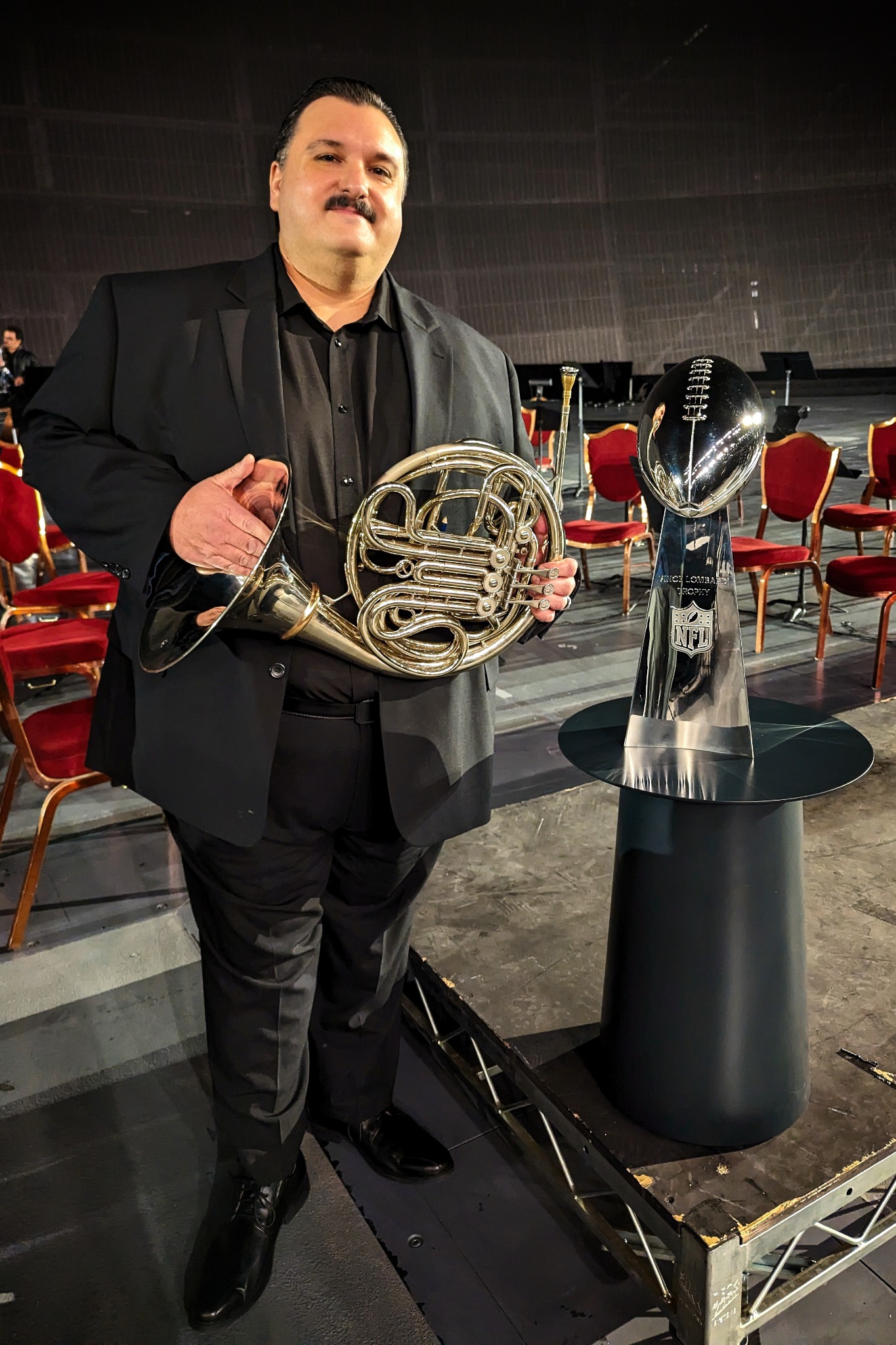 Jonathan Snyder holding his horn beside the Vince Lombardi Trophy